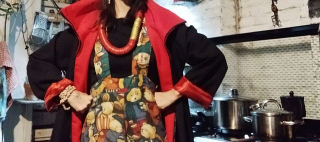 Suetszu, long hair, wearing dungarees with lots of printed illustrated teddy bears, and a sort of vampire coat.